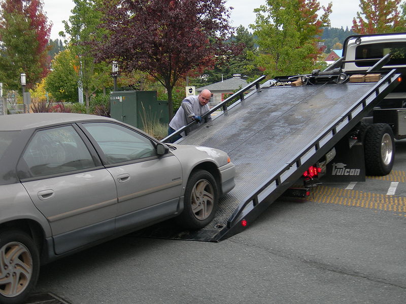 Car being loaded onto flat bed tow truck