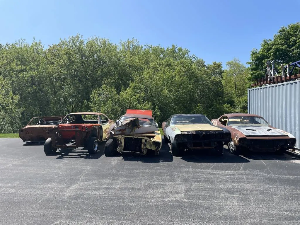 A 1970 Roadrunner, 1970 Charger, two Plymouth 'Cudas and a Pontiac Firebird in the back lot at SpeedKore awaiting their restomod fates.