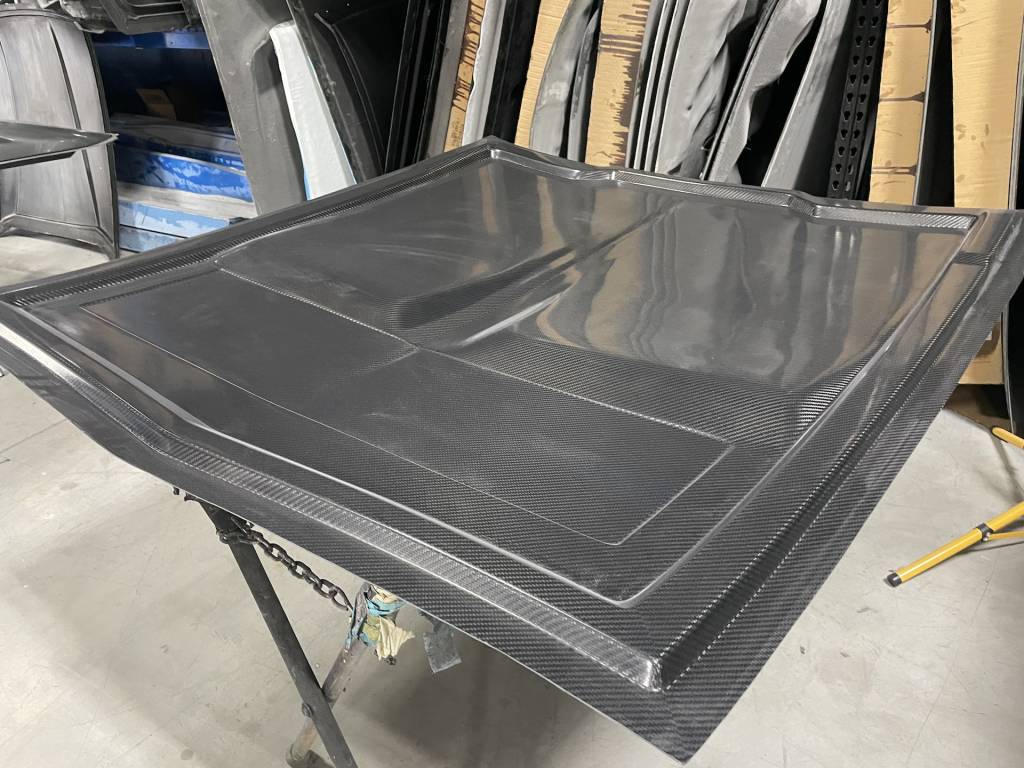 A 1970 Plymouth Barracuda on the rotisserie for paint prep and installation of heat shield in the tunnel and sound deadener in the floor. That carbon-fiber floor is also shown, as is a carbon-fiber hood.