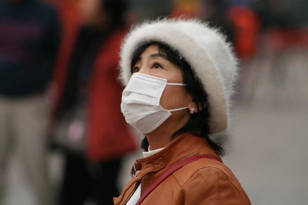Woman with smog mask (pic by Nicolò Lazzati on Flickr)