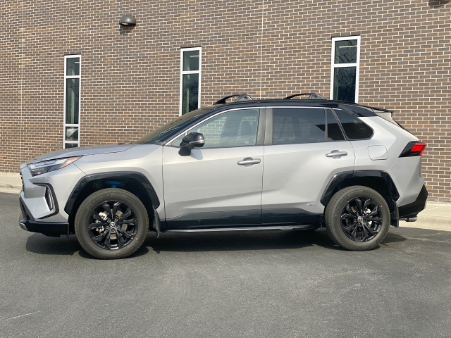 The 2023 Toyota RAV4 Hybrid XSE AWD sports SUV add-ons such as mud guards, running boards, a roof rack, and even blue coil springs poking through chunky wheel arches. 